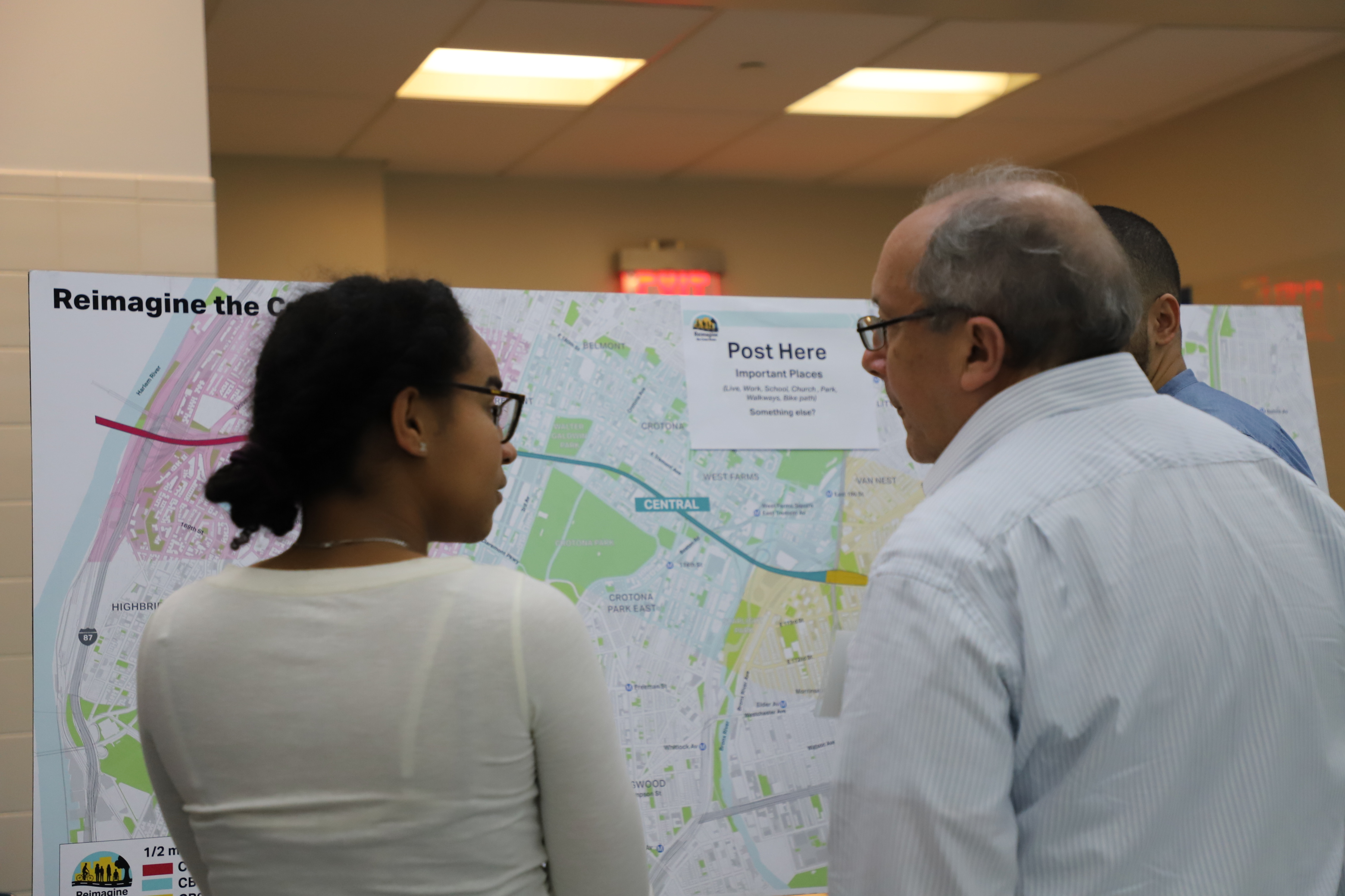 People have a conversation while standing in front of a map of the Cross Bronx Expressway project area