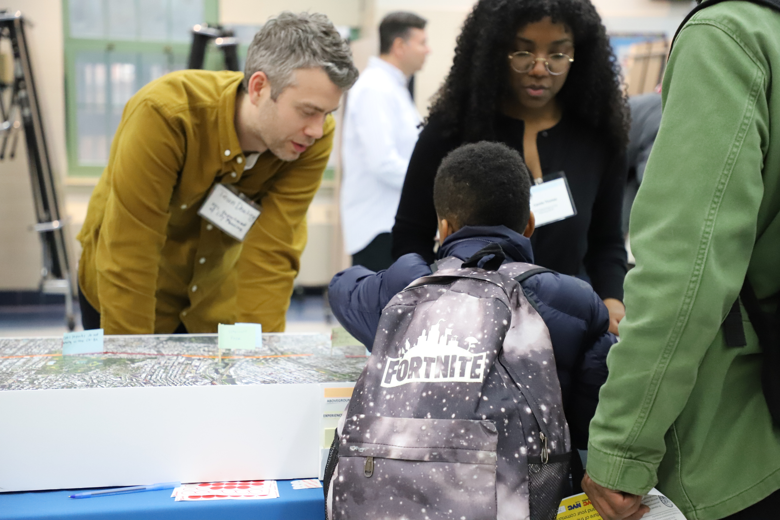 A child attends a public workshop and leans over a large map 