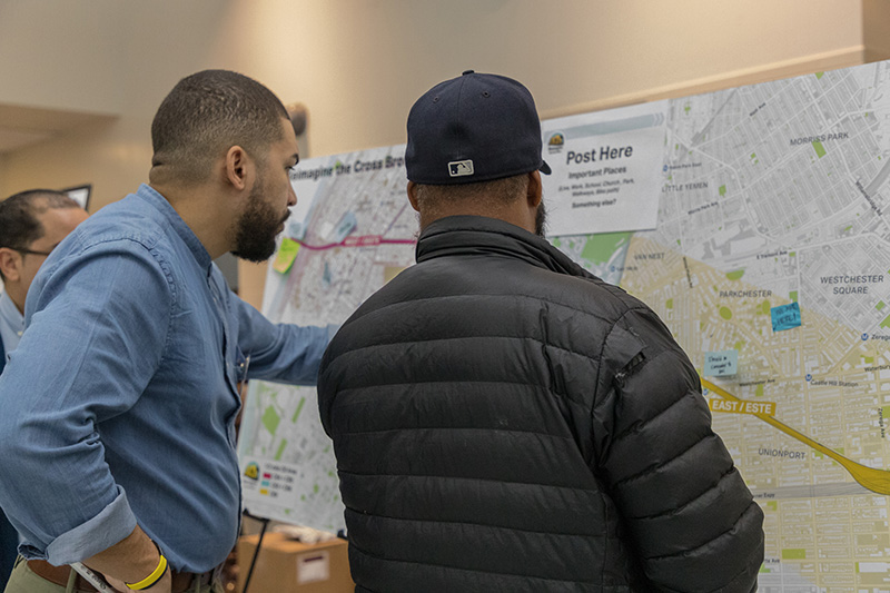 Two men have a conversation while standing in front of a map of the Cross Bronx Expressway project area