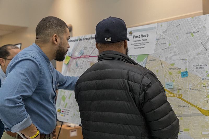 Dos hombres conversan frente a un mapa del área del proyecto Cross Bronx Expressway