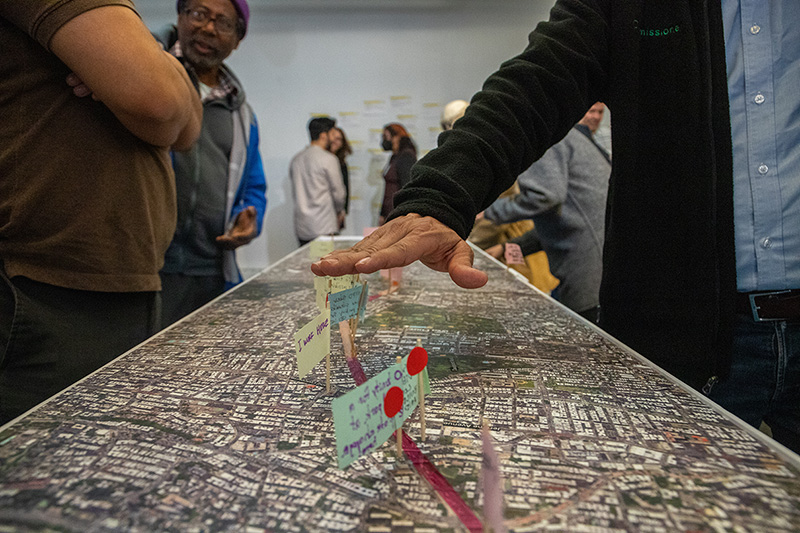 A man's hand hovers over a map with small flags with hand written messages