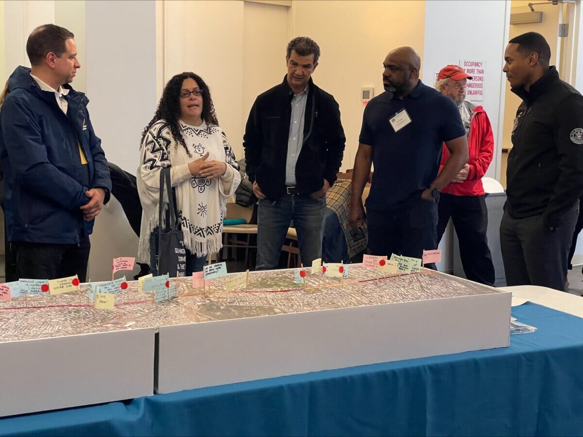 A group of people stand around a large map of the Cross Bronx Expressway at a public open house