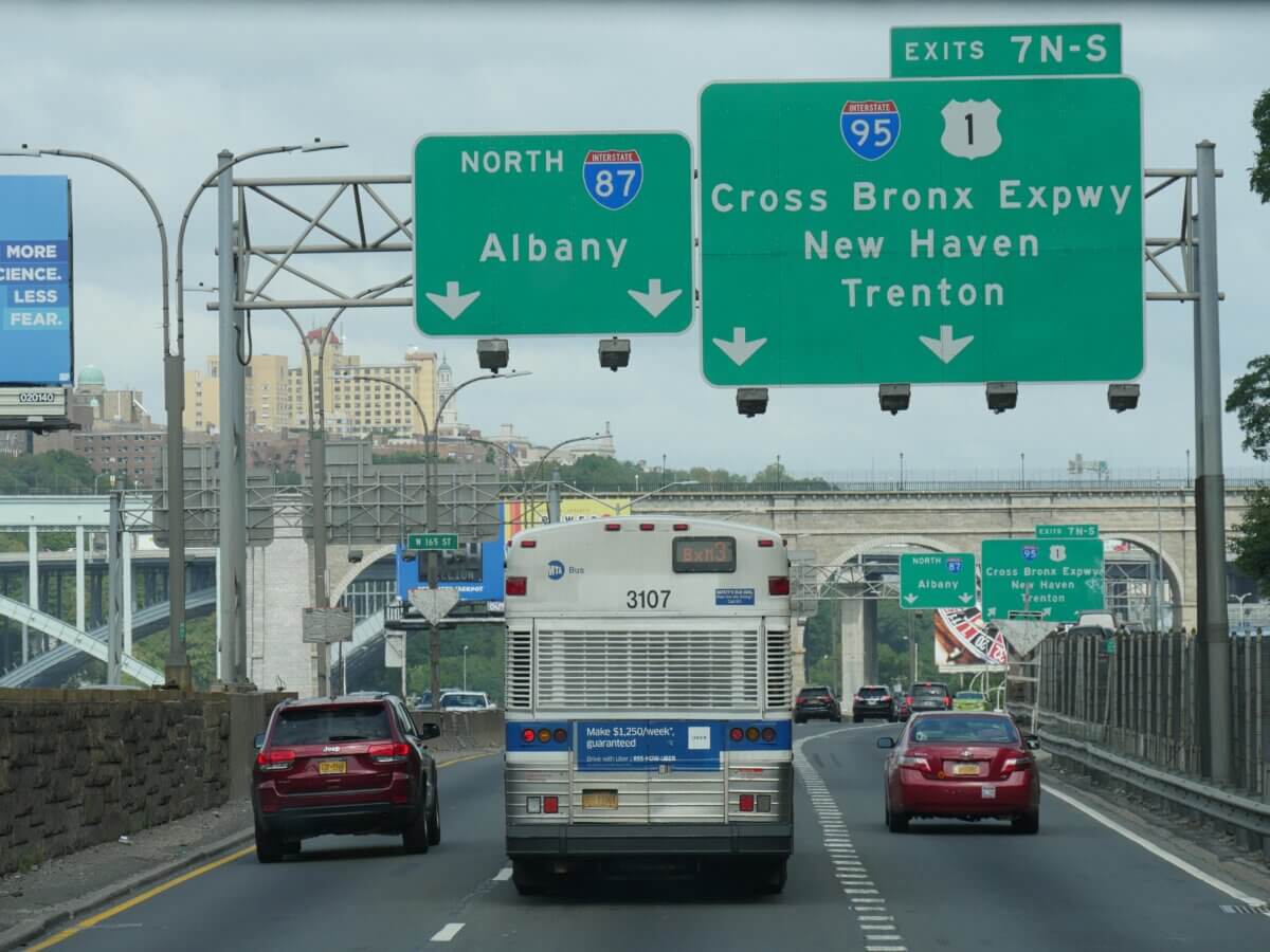 Cars and buses travel along a three lane highway in the Bronx